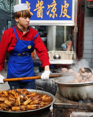 Image of a young man braising sheep hooves in Xi'an's Muslim quarter in China