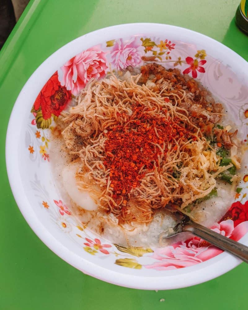 a bowl of congee dressed with several different condiments, planning a trip to thailand