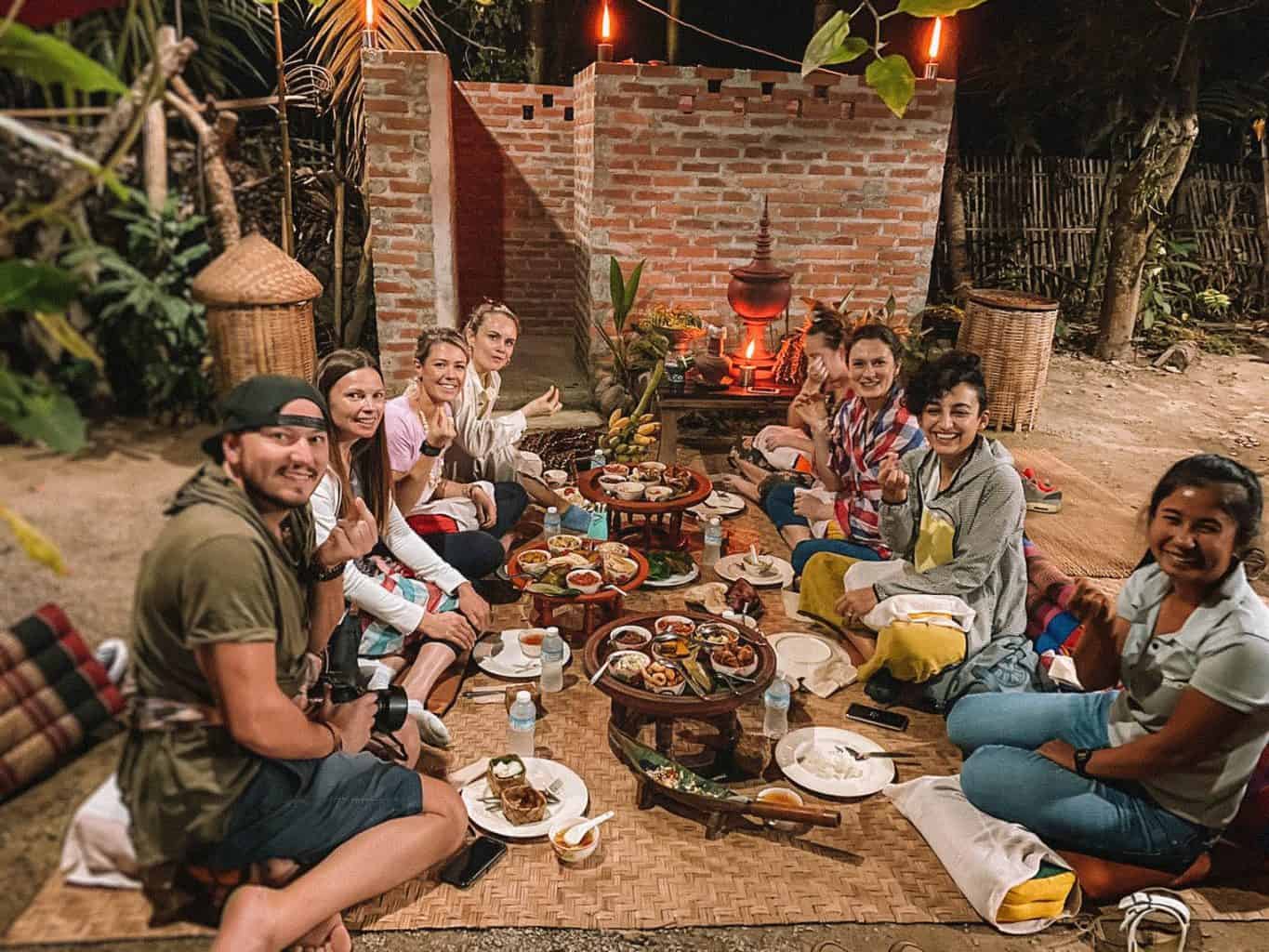 a group of G Adventures people sitting on the floor about to eat a meal