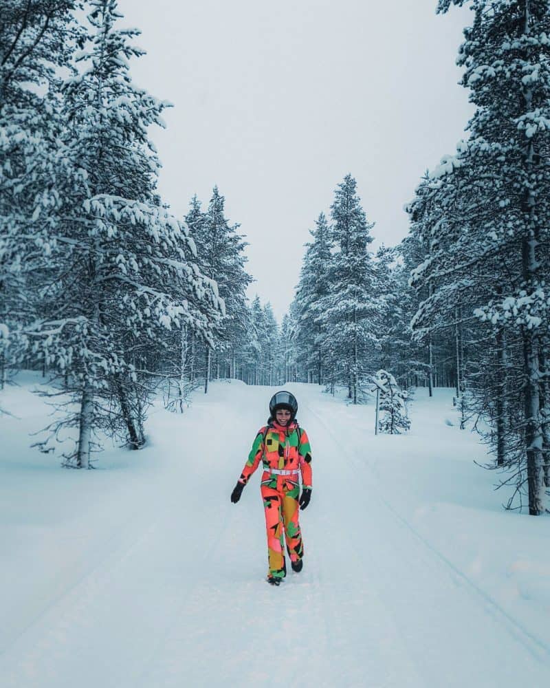 a woman in colourful winter gear walking in a snowy forest Finnish Lapland, Lapland destinations, Lapland Finland, Inghams