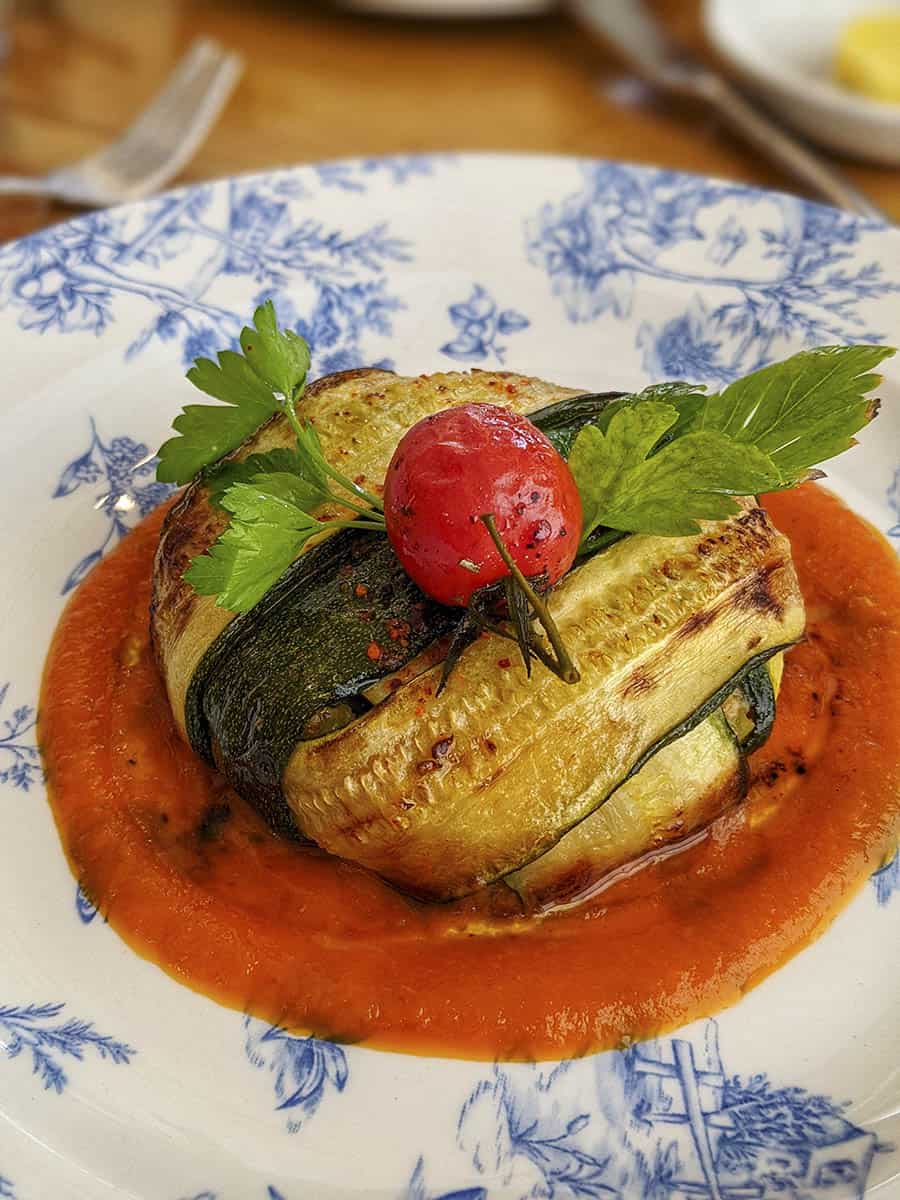 A dish of courgettes fashioned into a round cake on a tomato sauce base