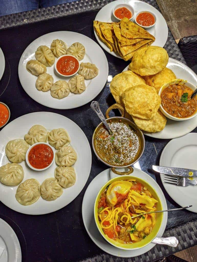 A delicious restaurant spread of various Nepalese dishes including daal, dumplings and noodle soup