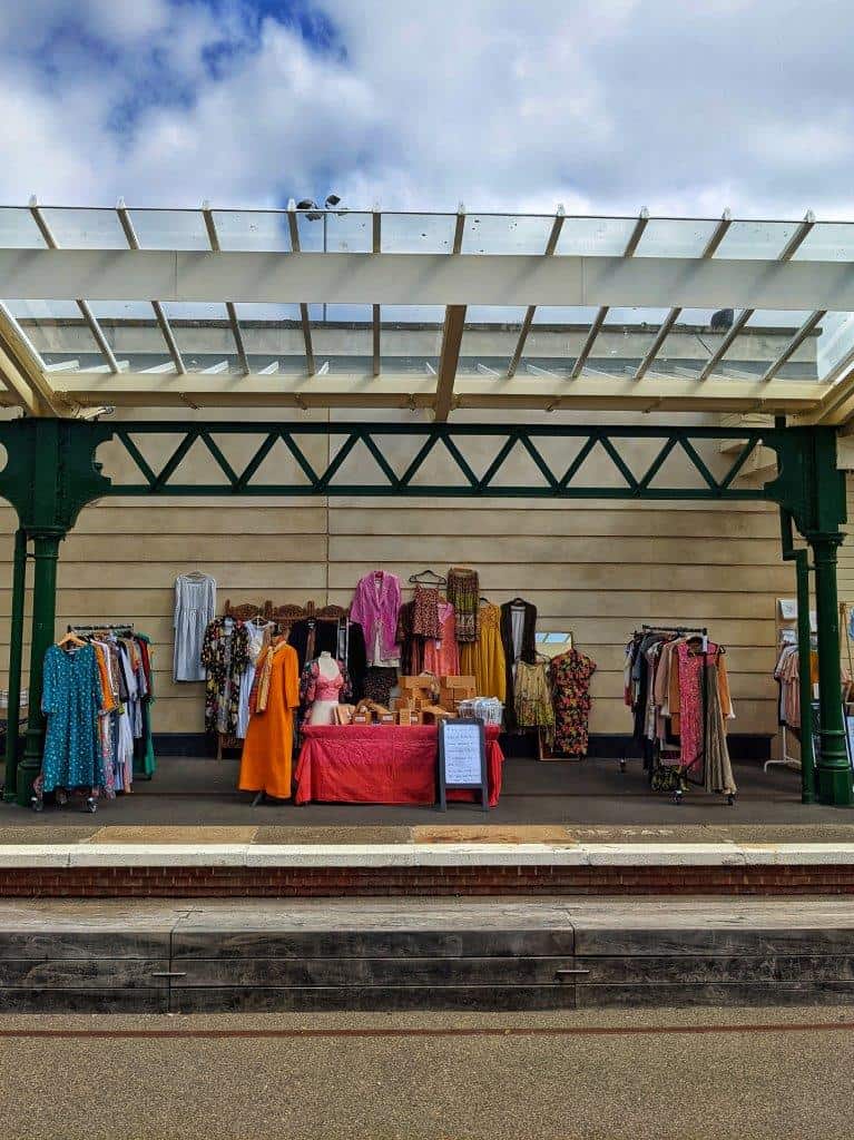 A colourful market stand on an ex-railway station platform displaying vintage clothing