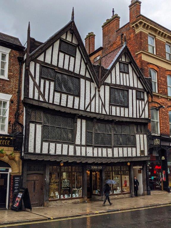 A classic black and white tudor building, the ground floor of which is a shop called 'York Gin'