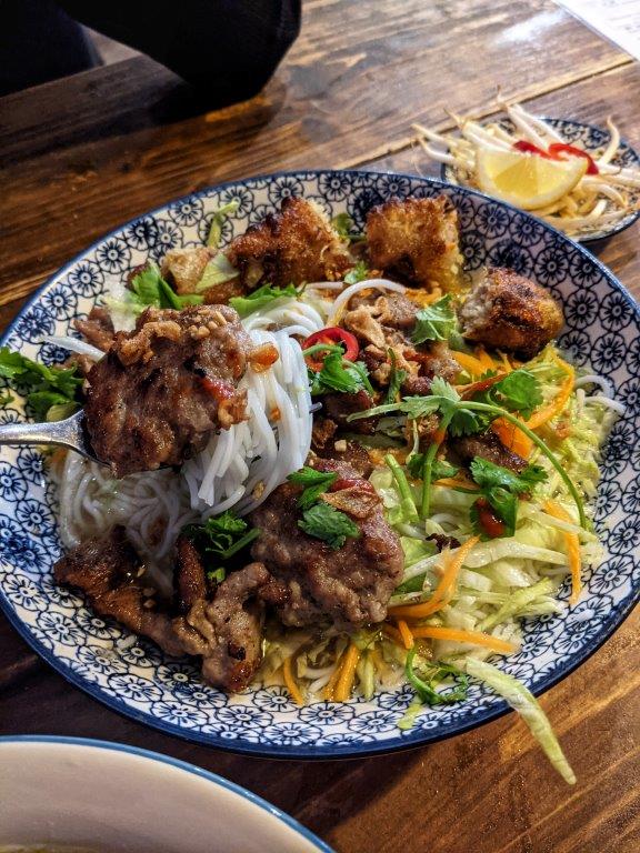 A vibrant dish of meat and vegetables on a decorative blue and white plate