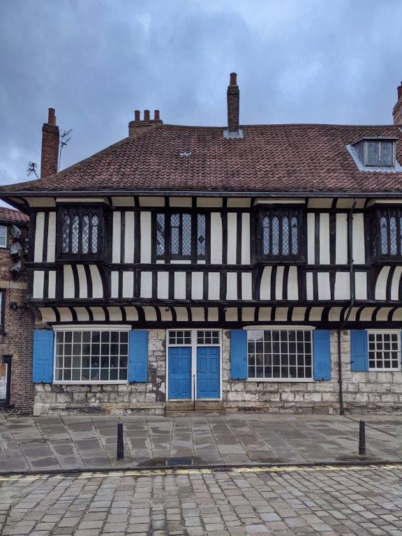 A classic black and white tudor style building with blue doors and window panels