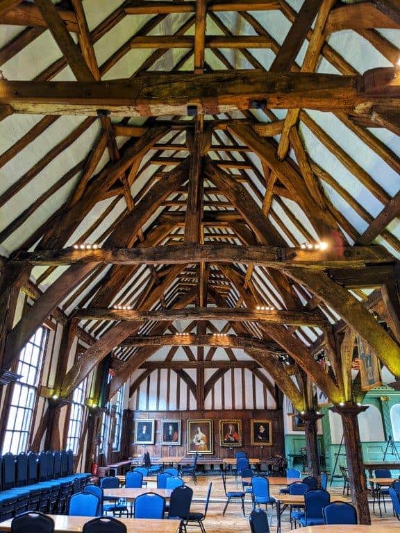 A view of the length of a grand medieval hall with a number of exposed wooden beams in the vaulted ceiling