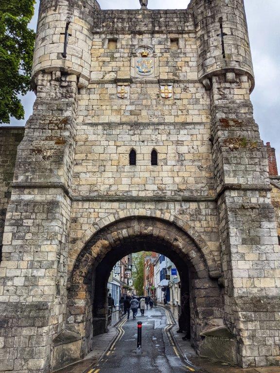 An imposing stone tower with an archway through which pedestrians can walk