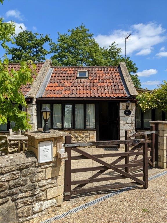 A stone cottage with terracotta tiled roof and a gated entrance