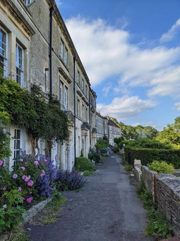 View down a walkway lined with beautiful Georgian style stone houses and pretty planting at the front of them