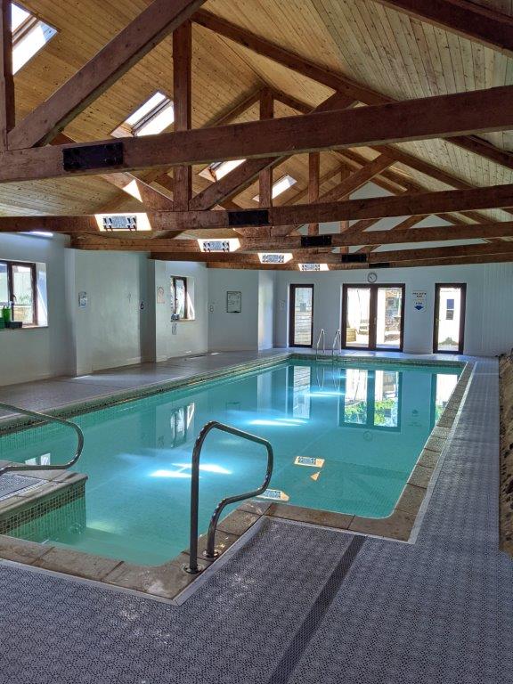 An indoor swimming pool set inside a converted barn with exposed wooden beams