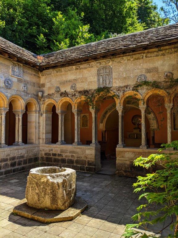 A garden courtyard in the style of ancient Rome with stone arches enclosing a central space